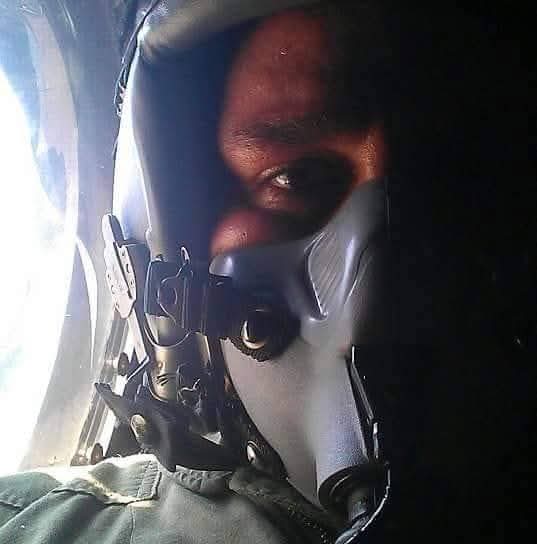 Person wearing a helmet with face partially visible, in a dark environment, with a bright background on the left side.