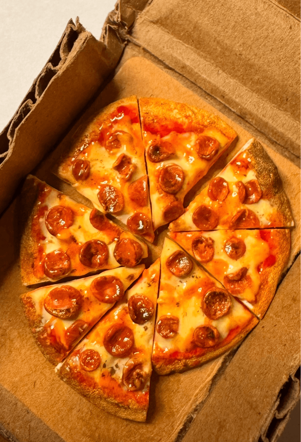 Pizza with pepperoni slices in a cardboard box, one slice slightly separated from the rest.