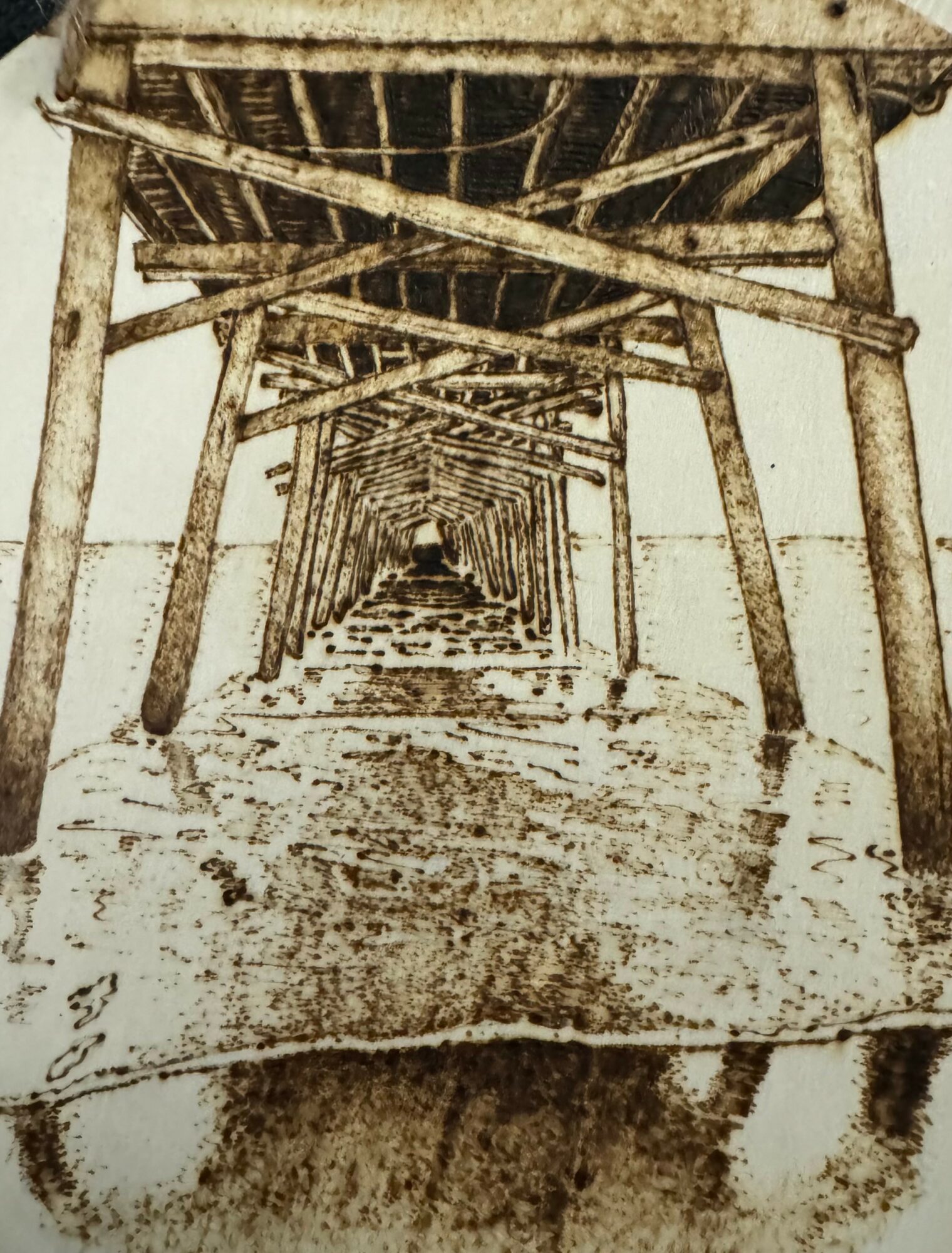 Underneath view of a wooden pier or dock structure with multiple supports and beams extending into the distance.