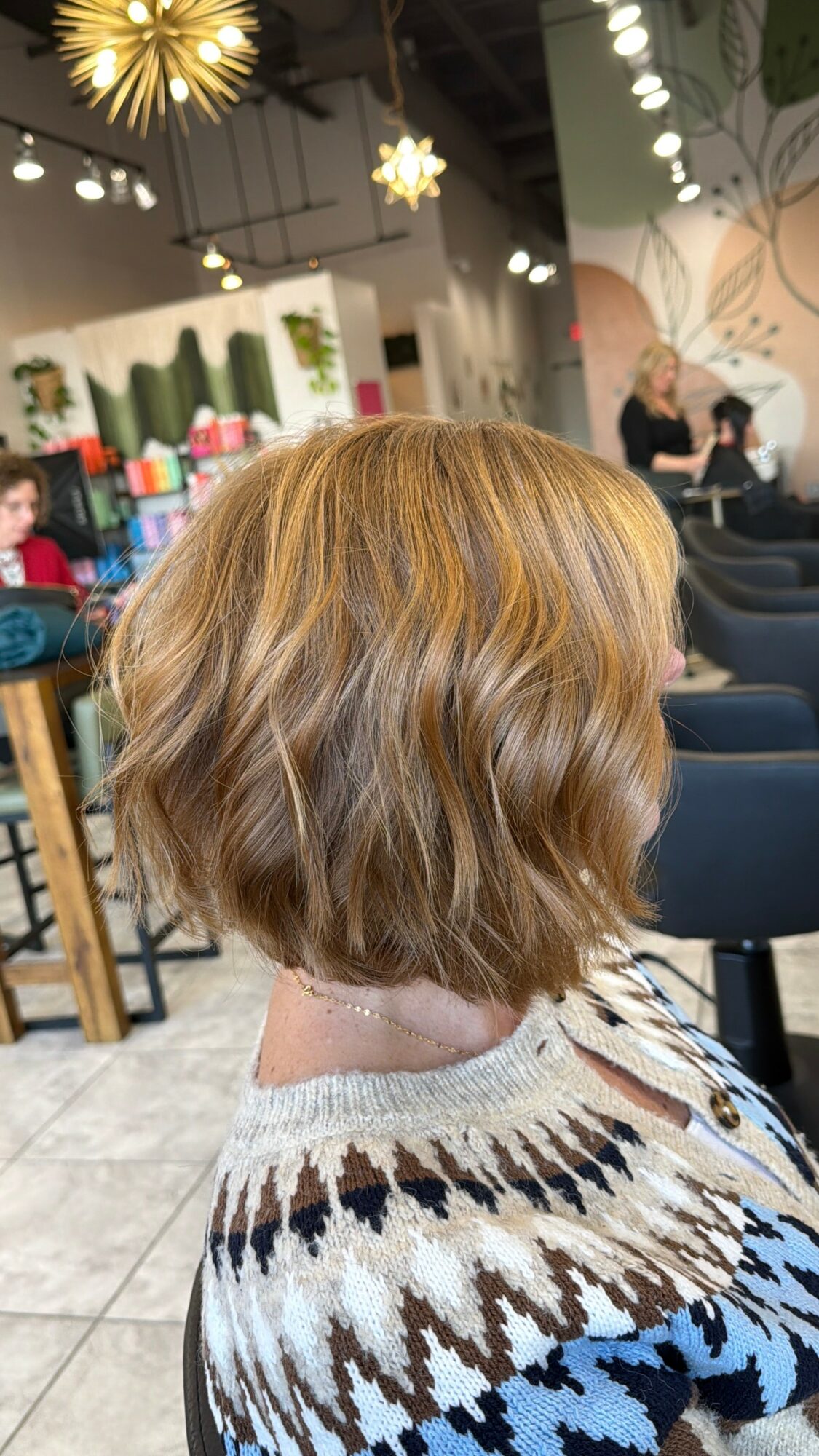 Side view of a woman with short, wavy, blonde hair in a public indoor space.