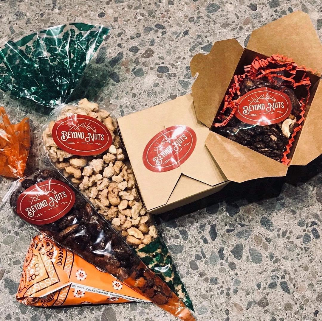 Assorted packaged snacks on a speckled surface, including a cone-shaped bag, boxes, and a plastic bag, all with red labels.
