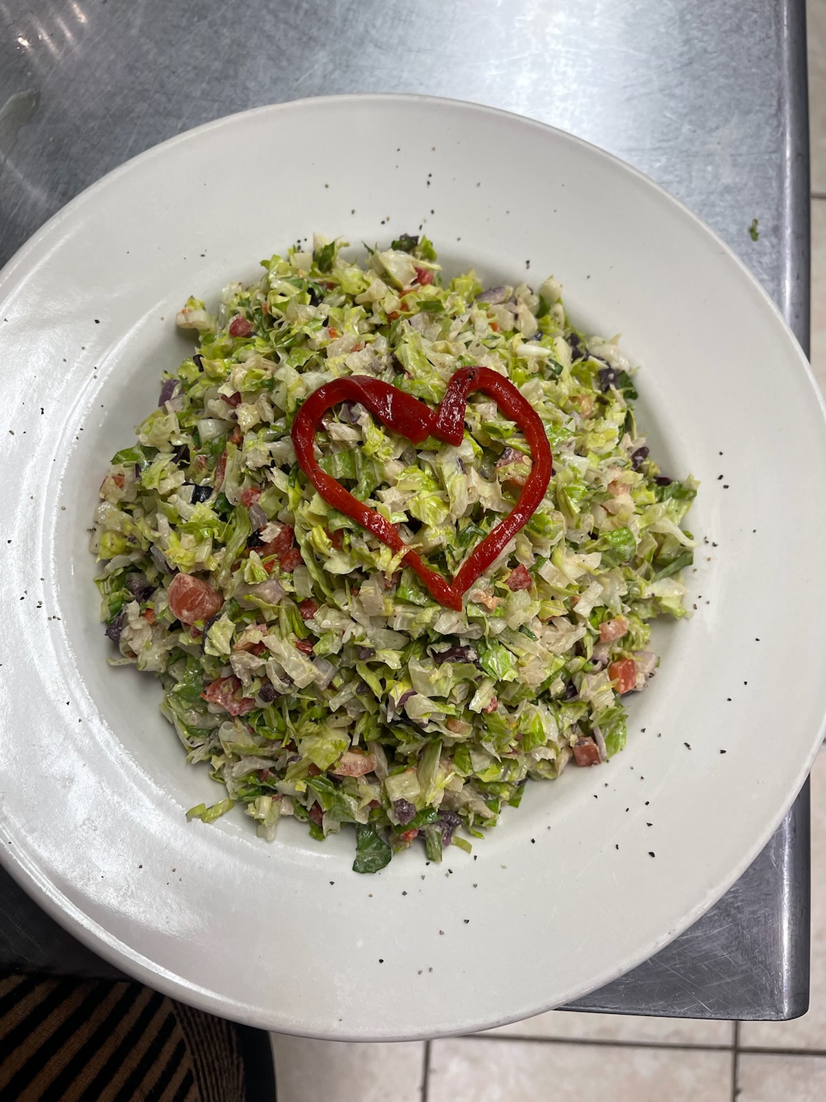 A plate of chopped vegetables with a heart shape made of red pepper on top.