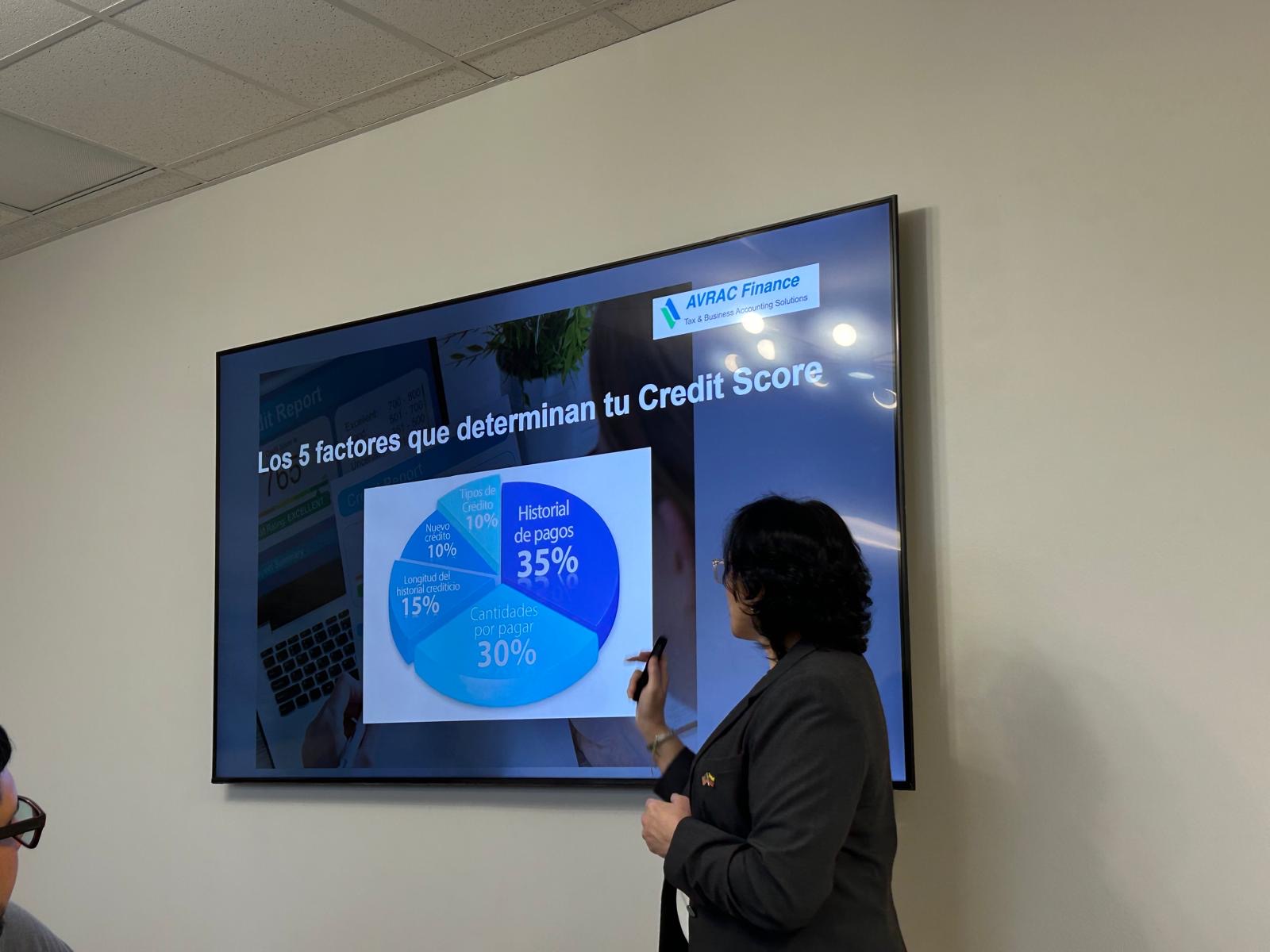 Person presenting a slide on a screen showing factors affecting credit score, including a pie chart with percentages.