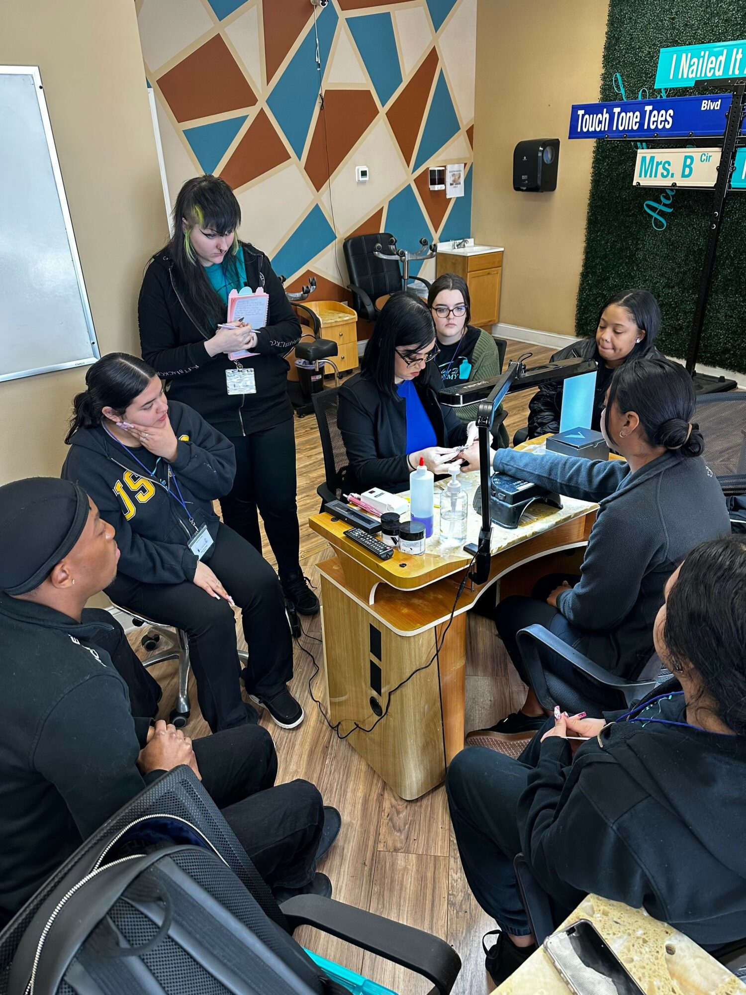 People gathered around a table with documents and a laptop in a room with geometric wall patterns.