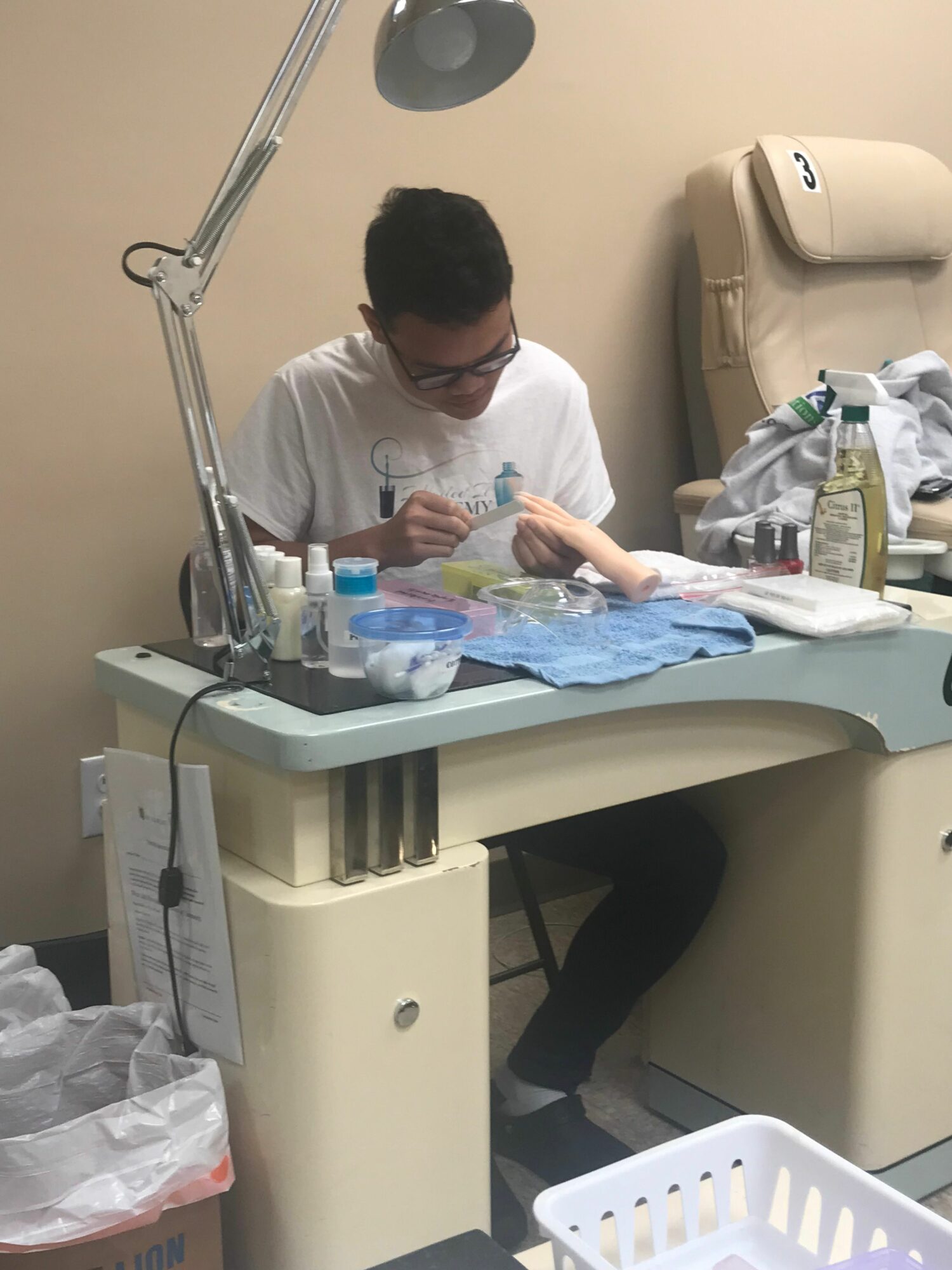 Person wearing glasses and white shirt working at a medical or laboratory table with supplies.