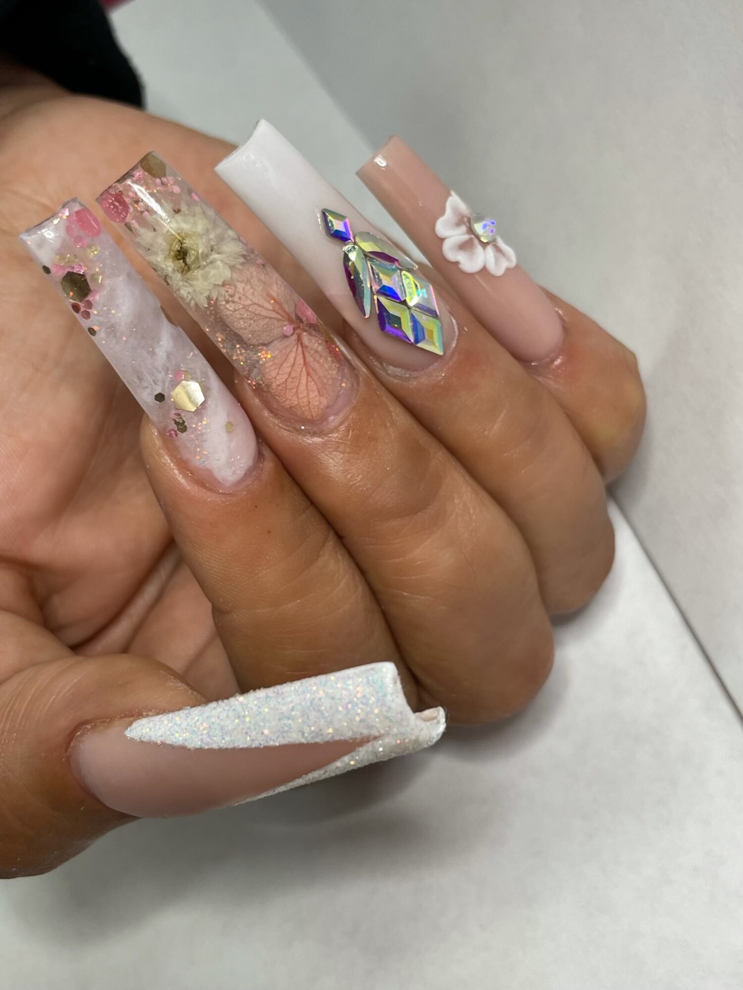 Close-up of a hand with decorated nails featuring various designs and colors.