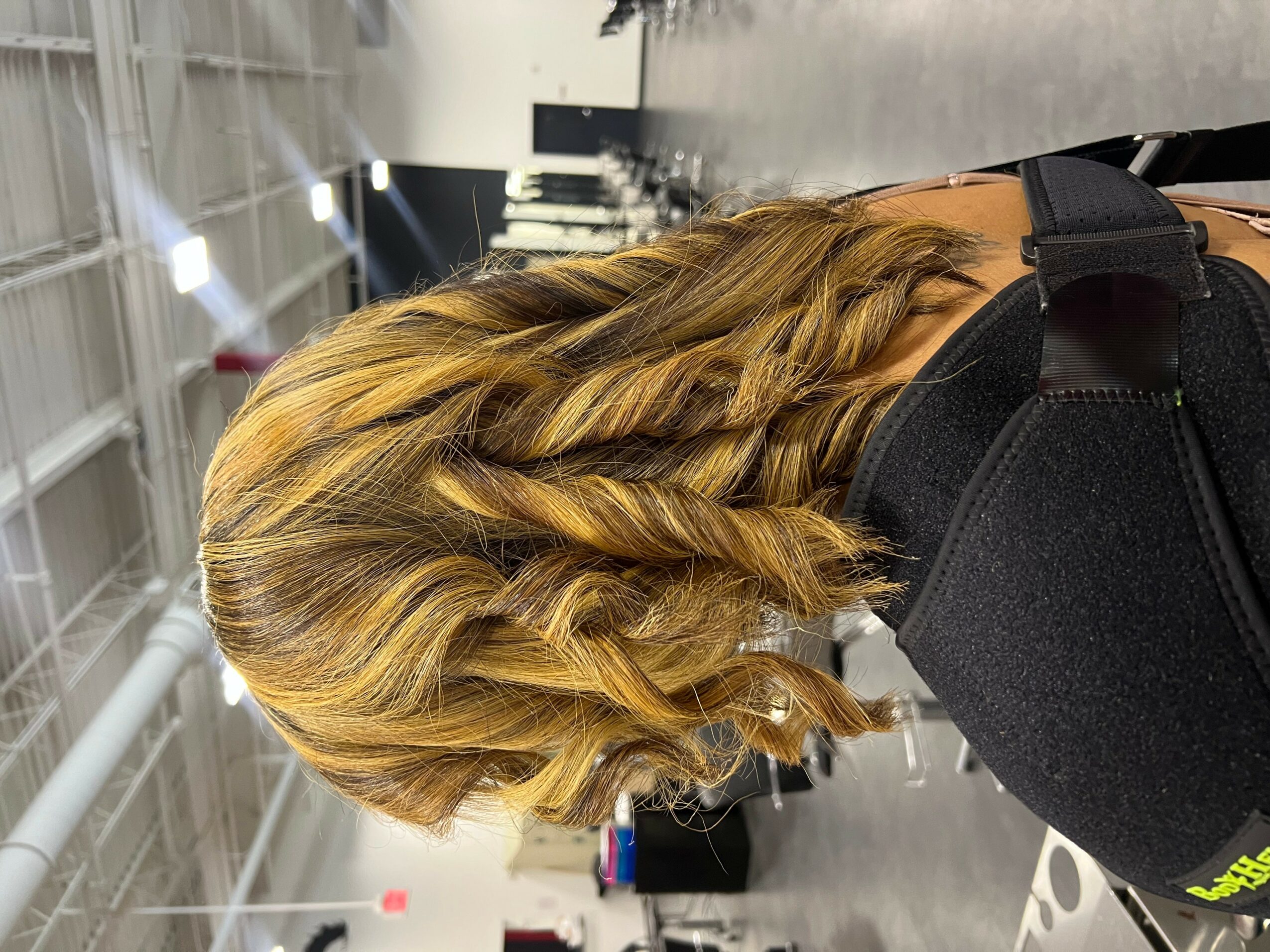 Side view of a woman with long, wavy, blonde hair in a large indoor space.