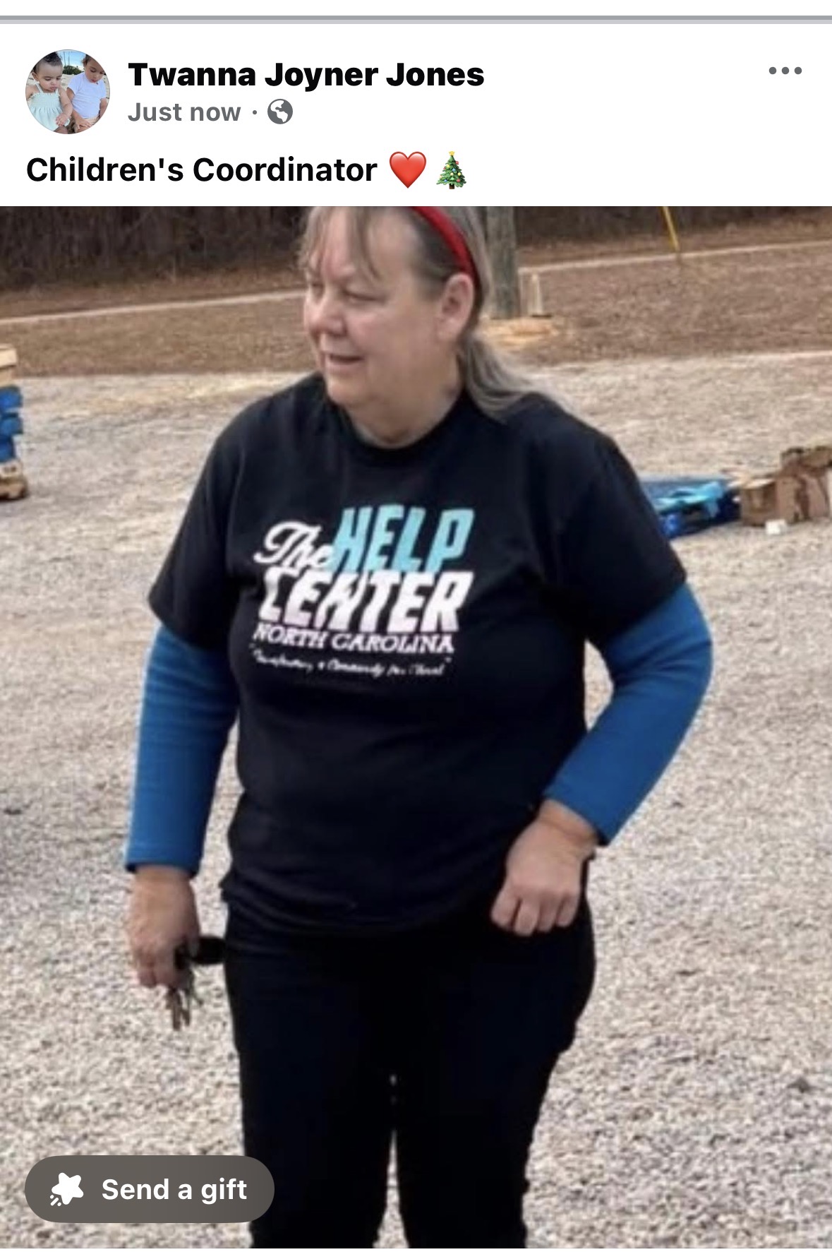 Woman with red headband wearing a black T-shirt and blue long sleeves outdoors, smiling, holding keys, gravel ground background.
