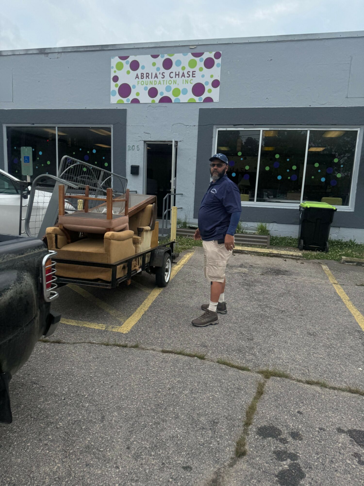 Person walking past a cart with chairs outside a building with a colorful sign.