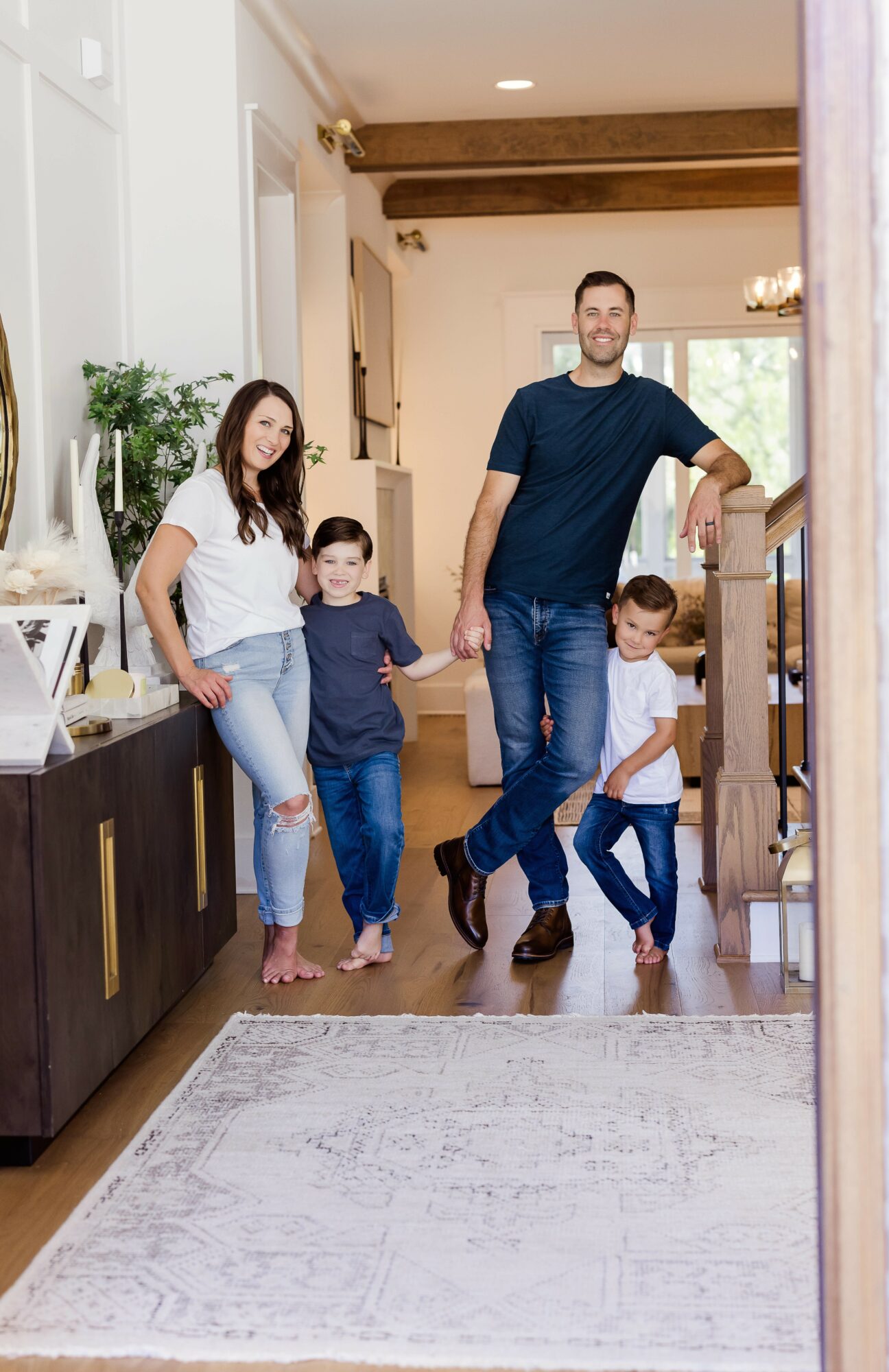 Family of four walking through a home, holding hands, with a man and woman and two children, in a bright living space.