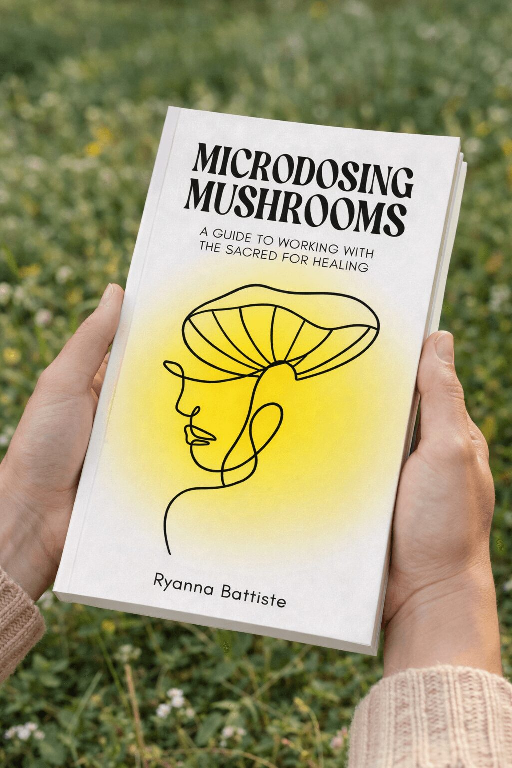 Person holding a book titled 'Microdosing Mushrooms' outdoors with grass background.
