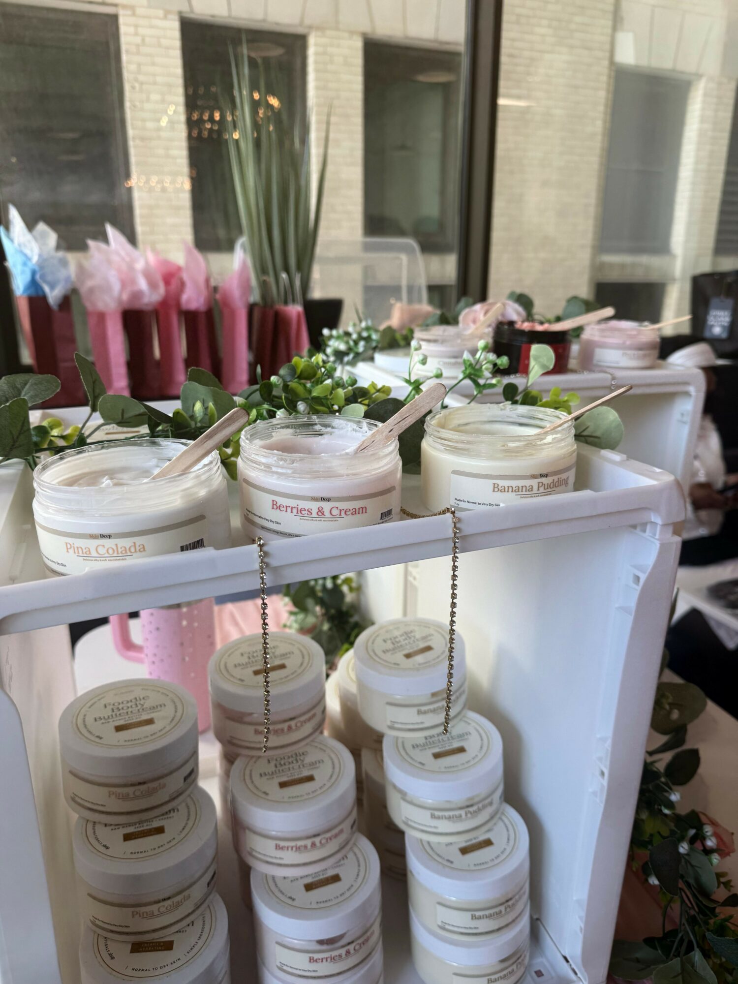 Display of skincare products with jars and bottles, decorated with flowers and pink accents, in a bright setting.