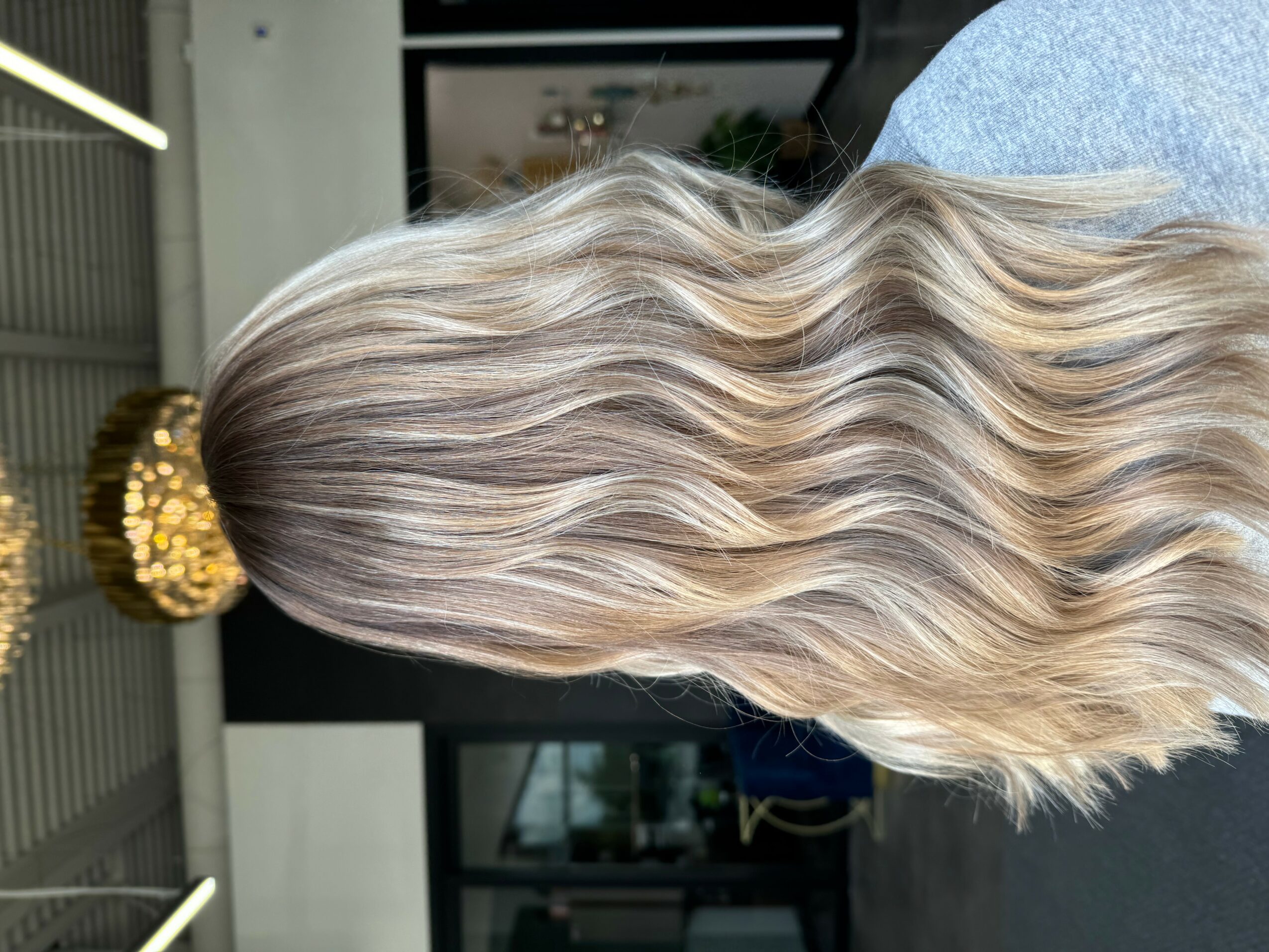 Side view of long, wavy, blonde hair with a decorative hair accessory, indoors.
