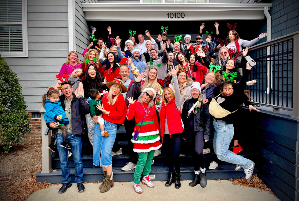 Group of people celebrating on steps outside a building, some wearing festive accessories, smiling and posing for the photo.
