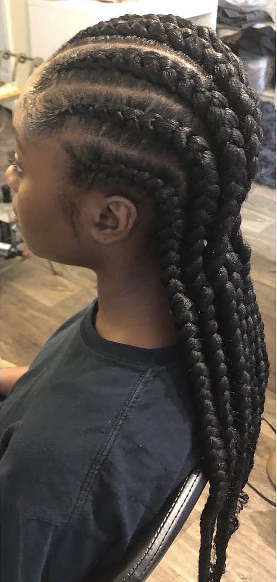 Side view of a person with long, thick, braided hairstyle, with cornrows on top and box braids hanging down.