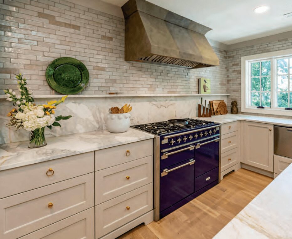 Kitchen with white cabinets, a black stove, marble countertops, brick wall, and a window with natural light.