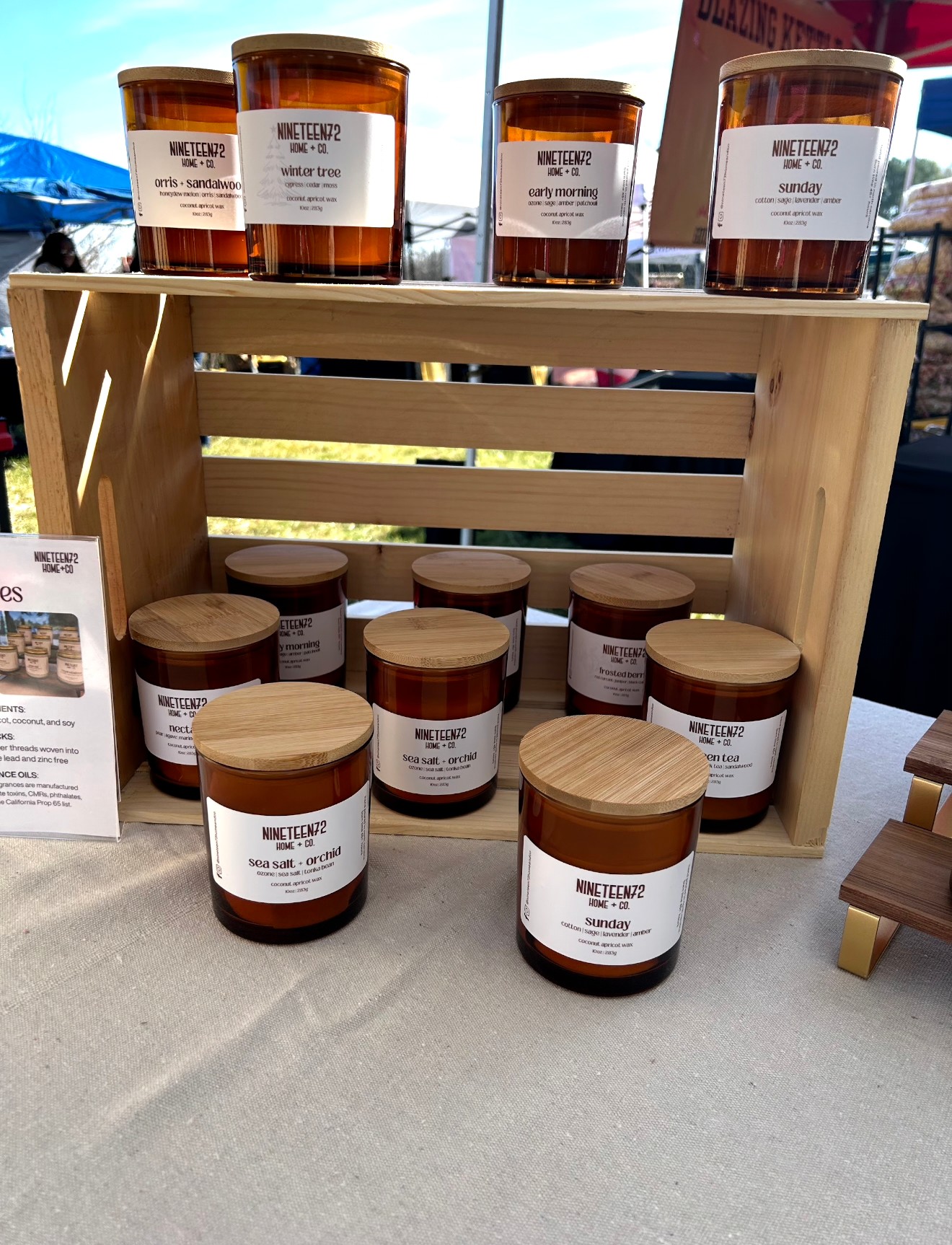 Wooden display box with jars of honey on a table outdoors, some jars on top and others inside the box.