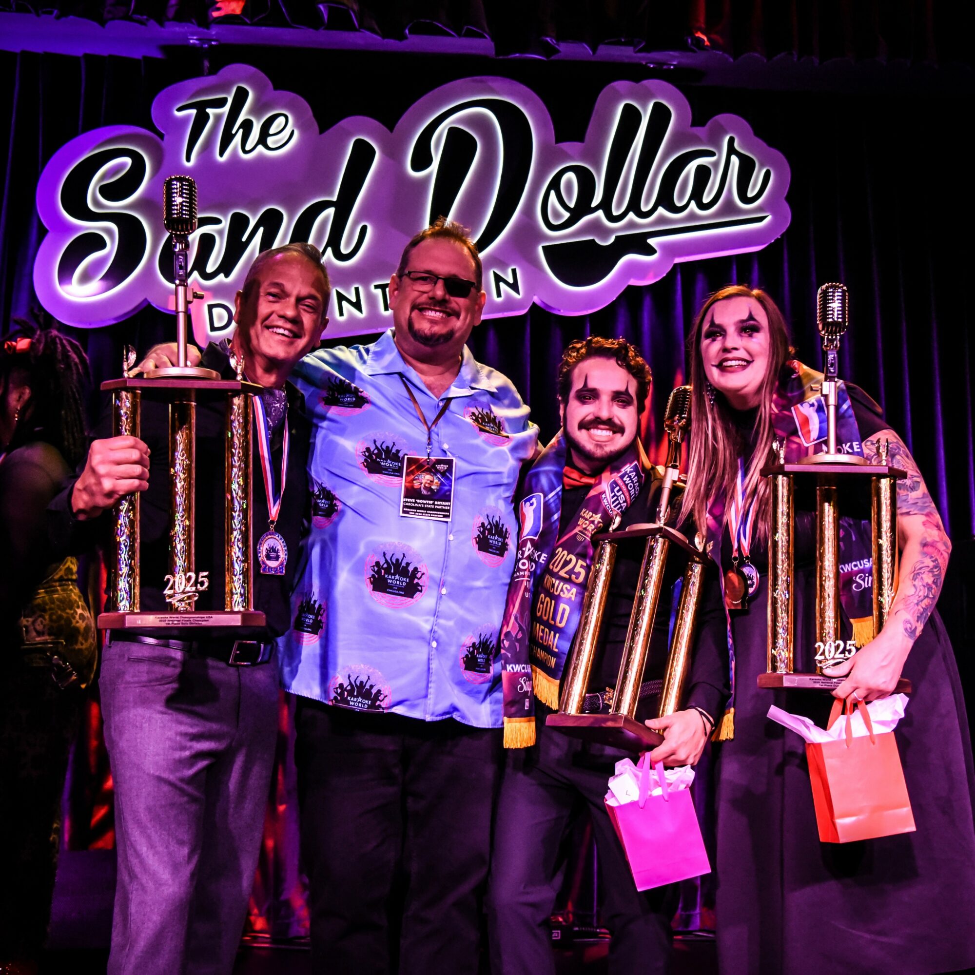 Four people on stage holding awards, smiling, with a sign reading 'The Sound Dollar' behind them.