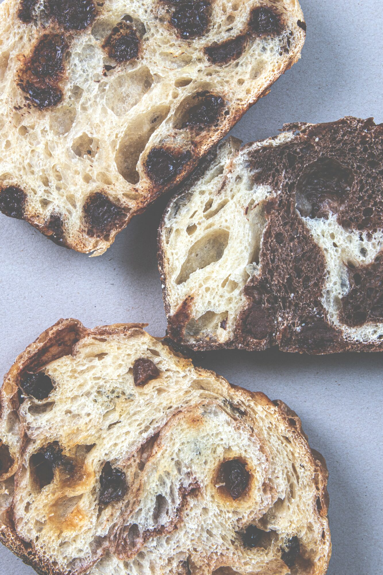 Three slices of marbled bread with dark and light swirls on a gray surface.