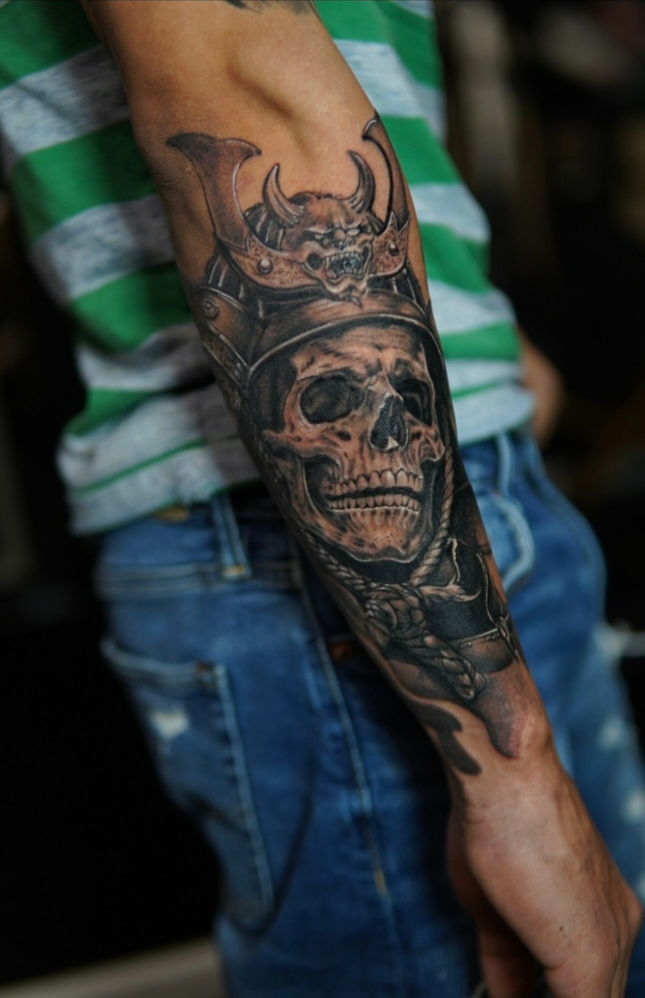 Tattoo of a skull with a Viking helmet on a person's arm, detailed and shaded in black and gray.