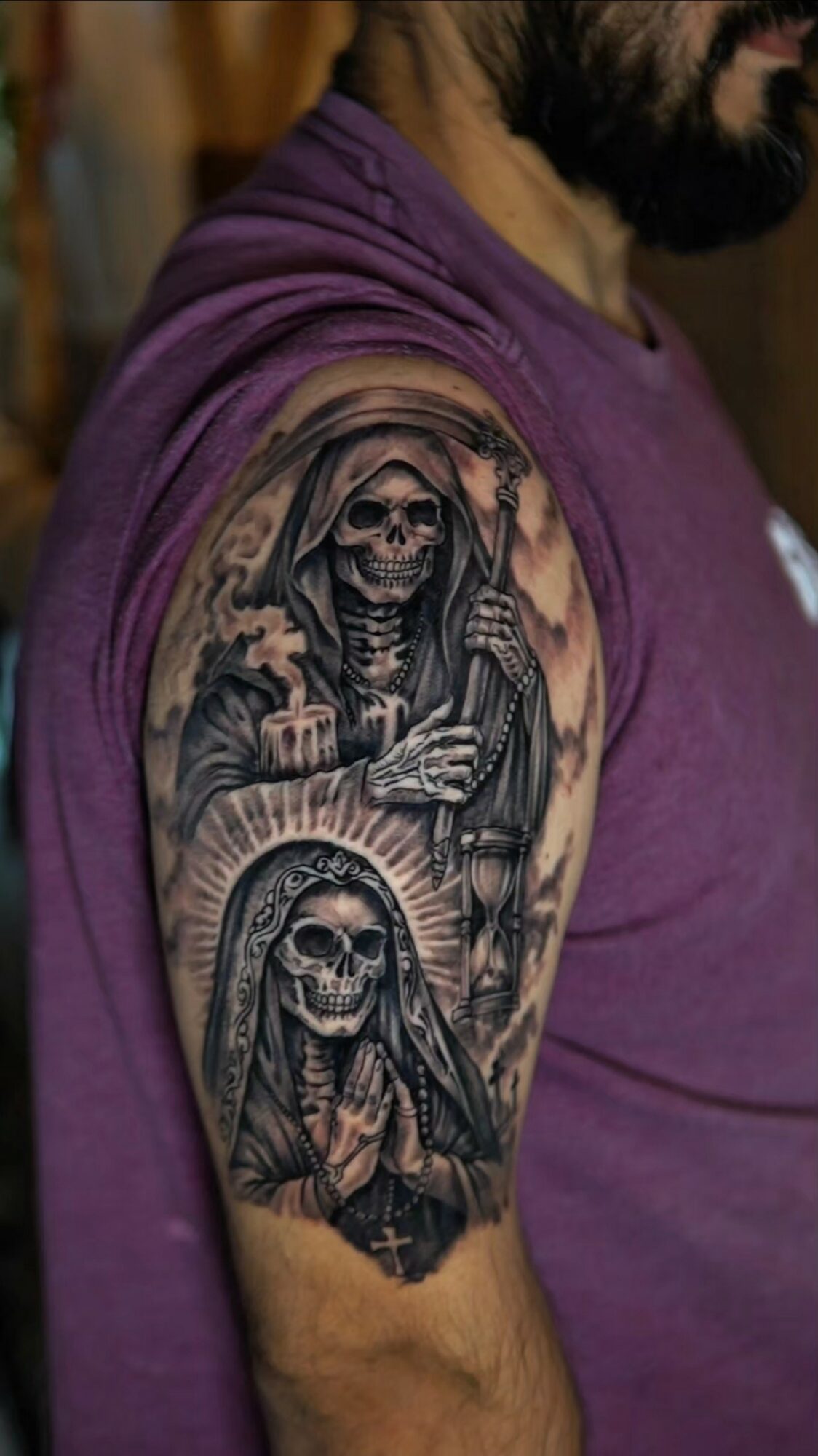 Tattoo of two skulls, one with a hood and the other with a crown, on a person's upper arm.