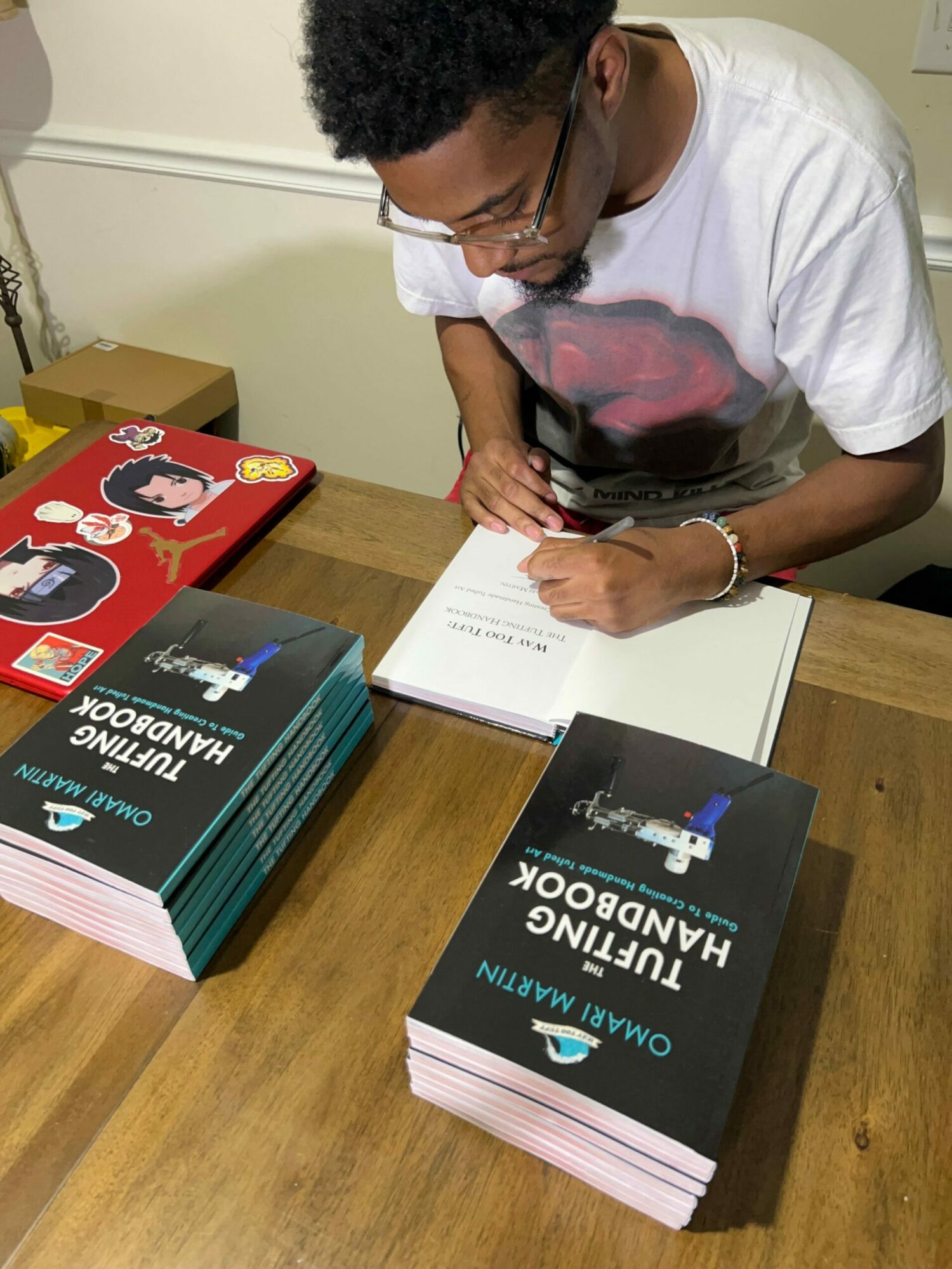 Person signing a book at a table with multiple copies of a book titled 'Quantum Computing Handbook'.