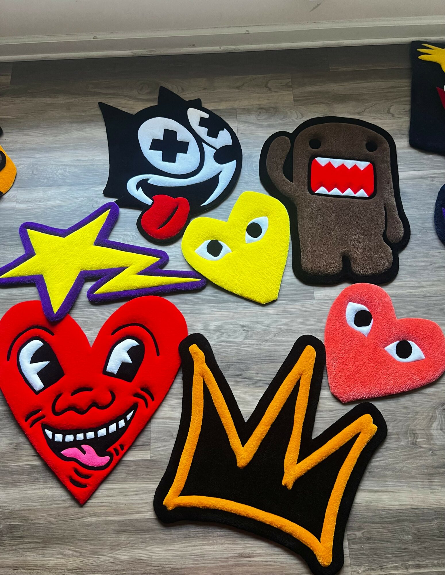 Collection of colorful patches including a black and white cat, a brown bear, a yellow heart, a red heart, a purple star, and an orange crown, on a wooden surface.