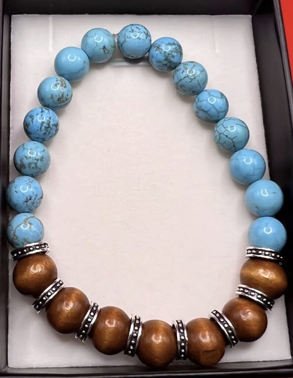 Beaded necklace with blue and brown beads, some with metallic accents, arranged in a circle inside a box.