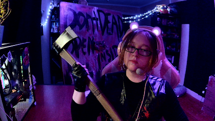 Person with glasses and pink hair holding a sword in a room with purple lighting and decorations.