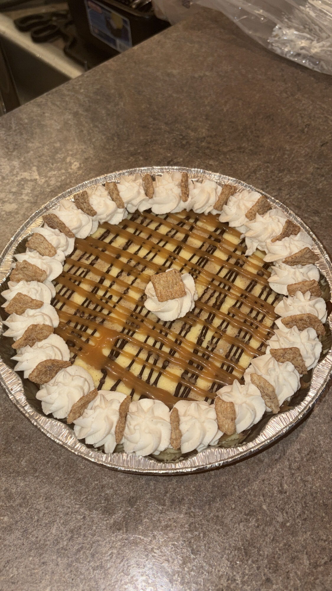 Round tray with small dollops of whipped cream or frosting arranged around the edge and a central dollop, on a dark surface.