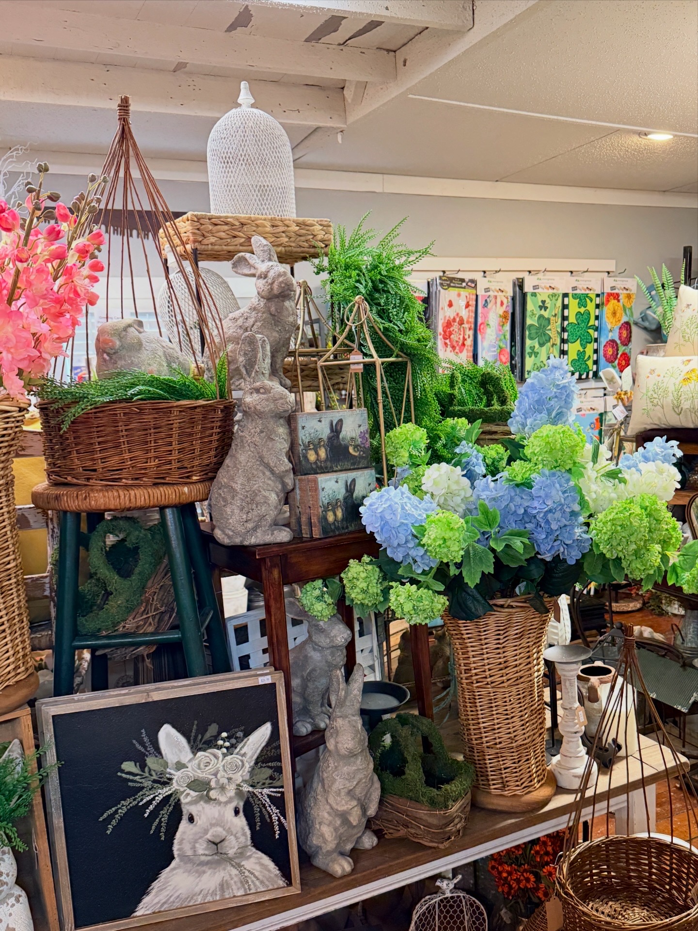 Display of flowers, baskets, and decorative items in a store, with colorful flowers and various ornaments.