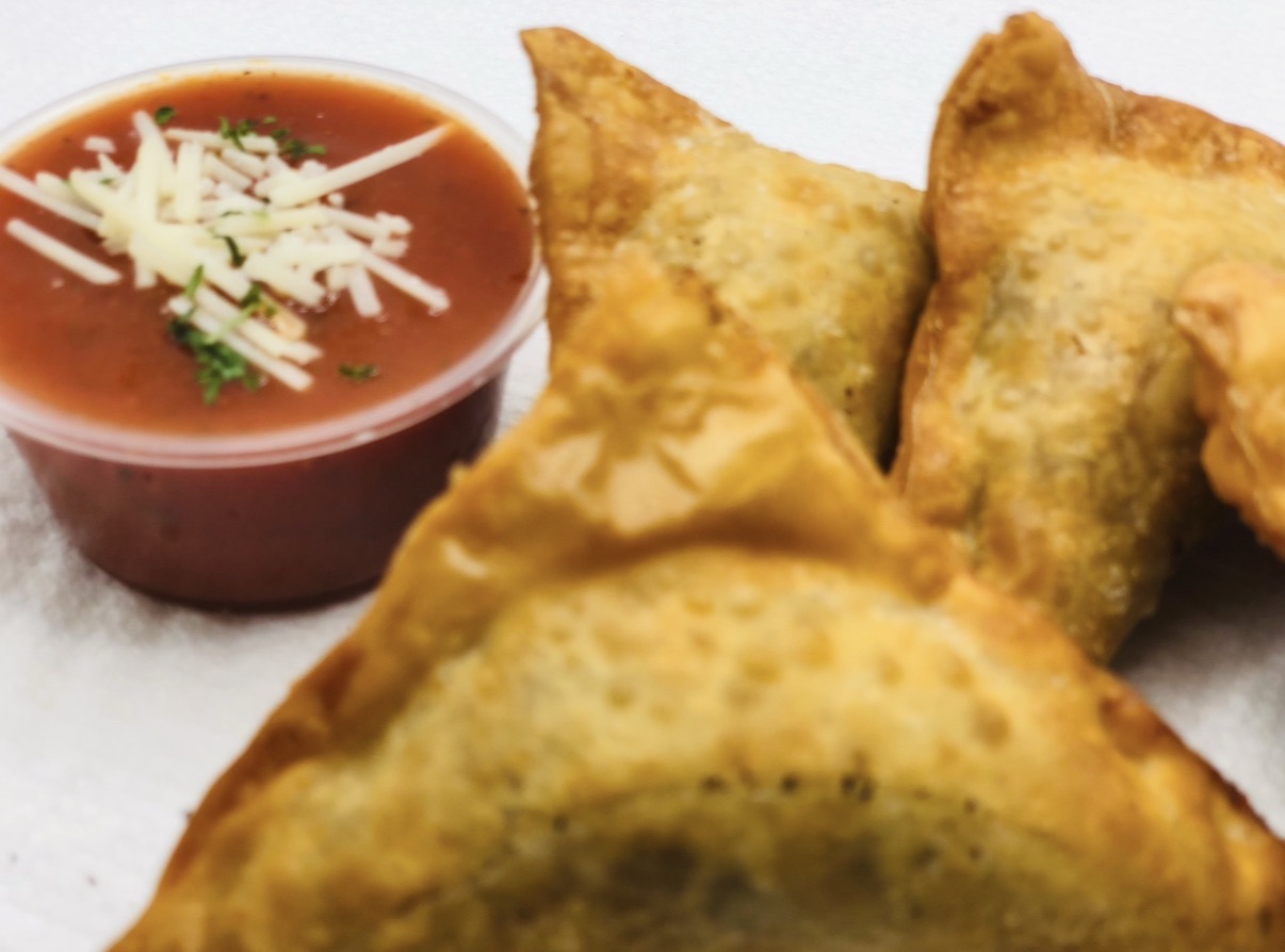 Fried food with a bowl of red sauce topped with shredded cheese and herbs, on white background.