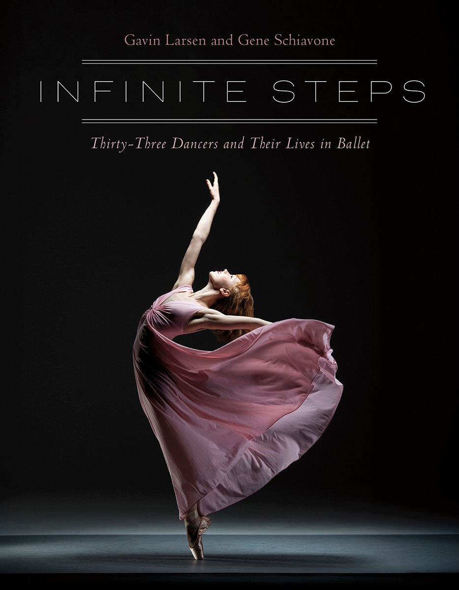 Ballet dancer in a pink dress performs a high leap with one arm raised, against a dark background.
