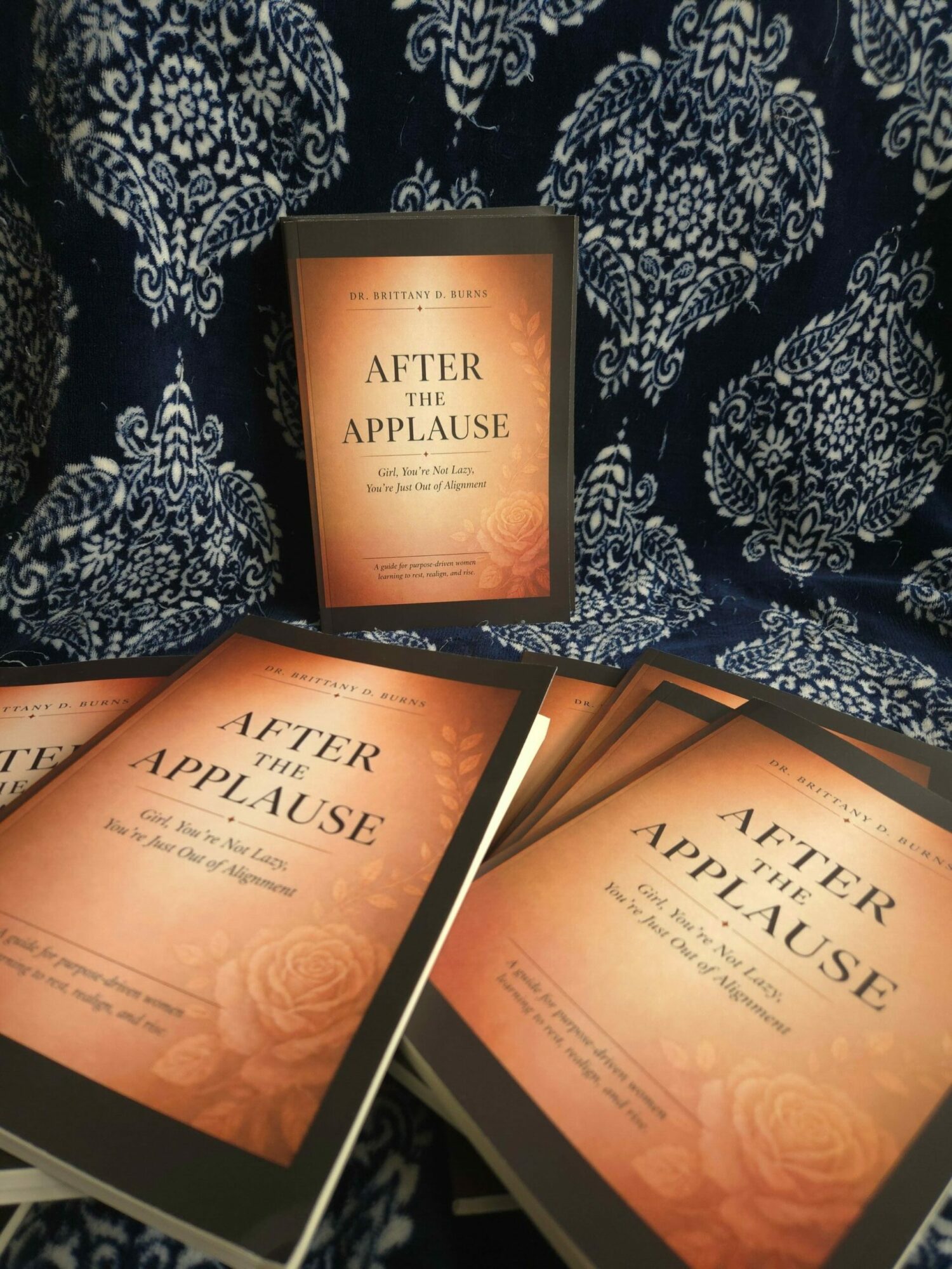 Three copies of a book titled 'After the Apocalypse' on a patterned fabric surface.