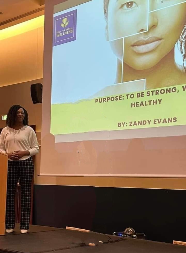 Woman standing in front of a presentation slide about health and strength, with a large image of a woman's face on the slide.