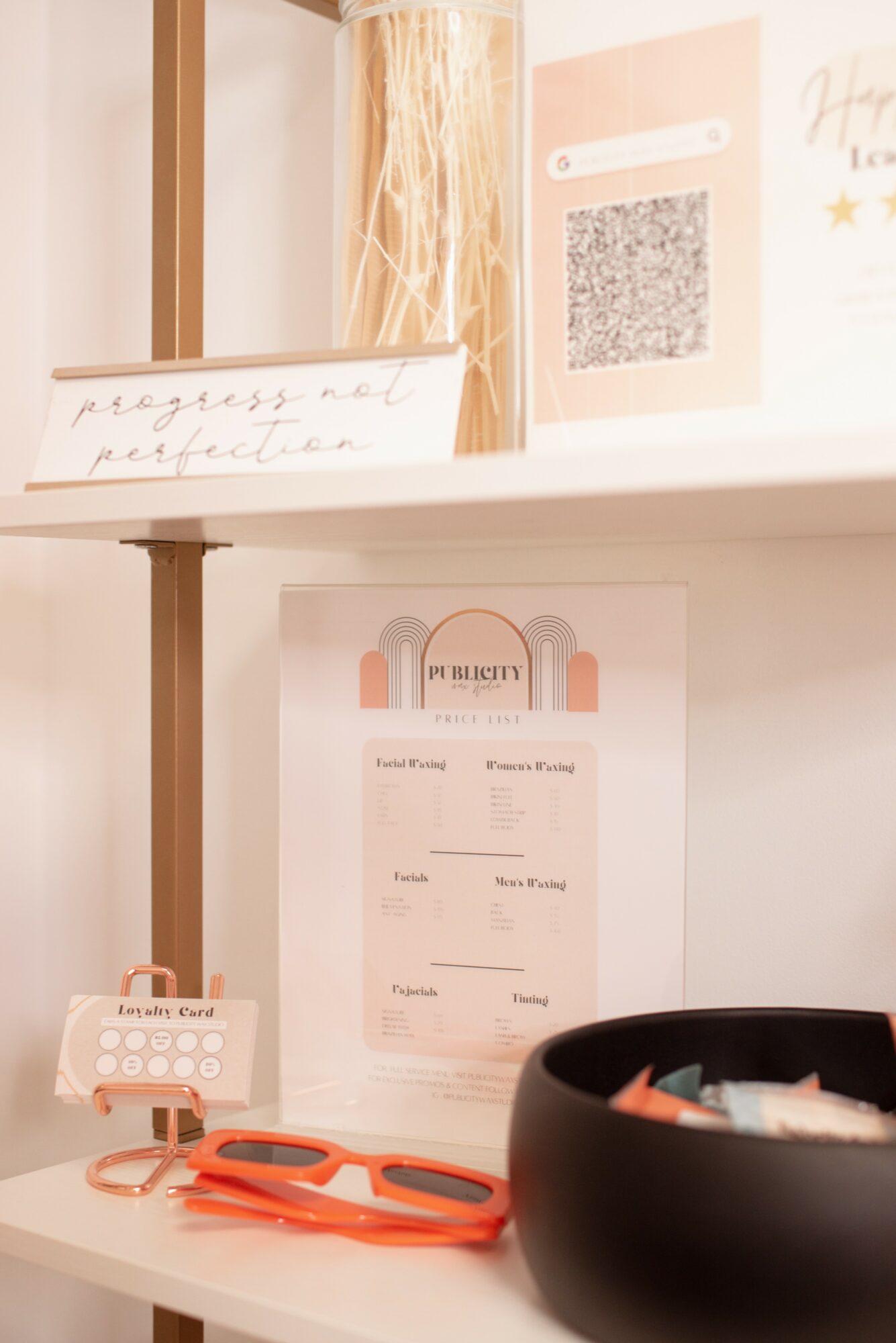 Desk with a black bowl, orange scissors, and a small sign, with a poster and QR code on the wall behind.