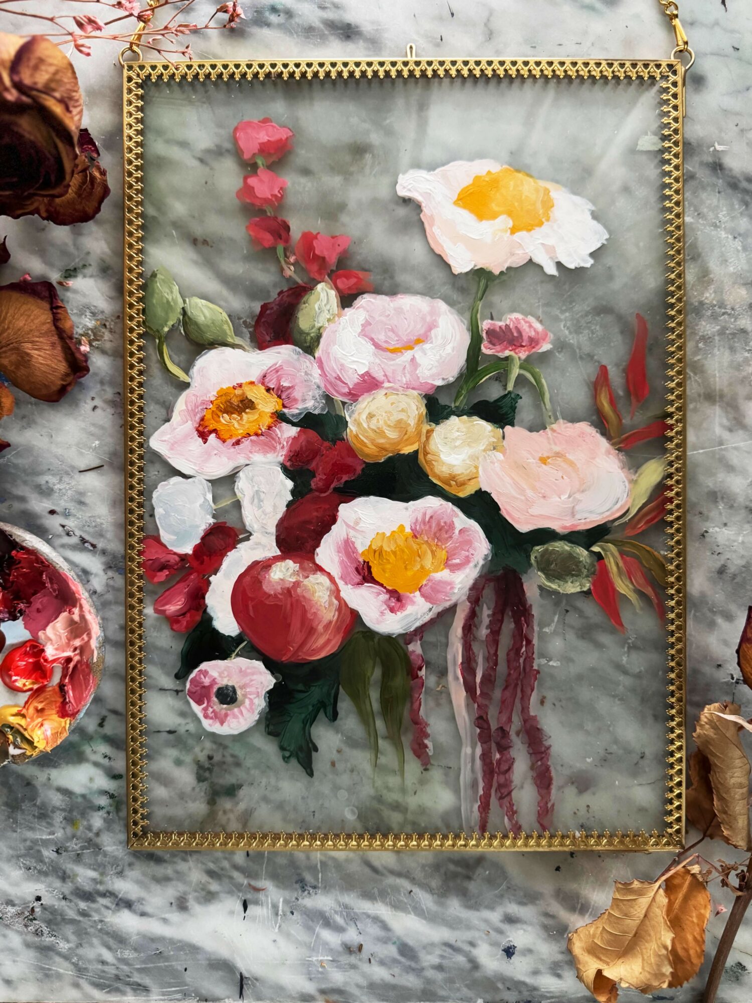 Framed floral painting with pink, white, and yellow flowers in a vase, on a marble surface.