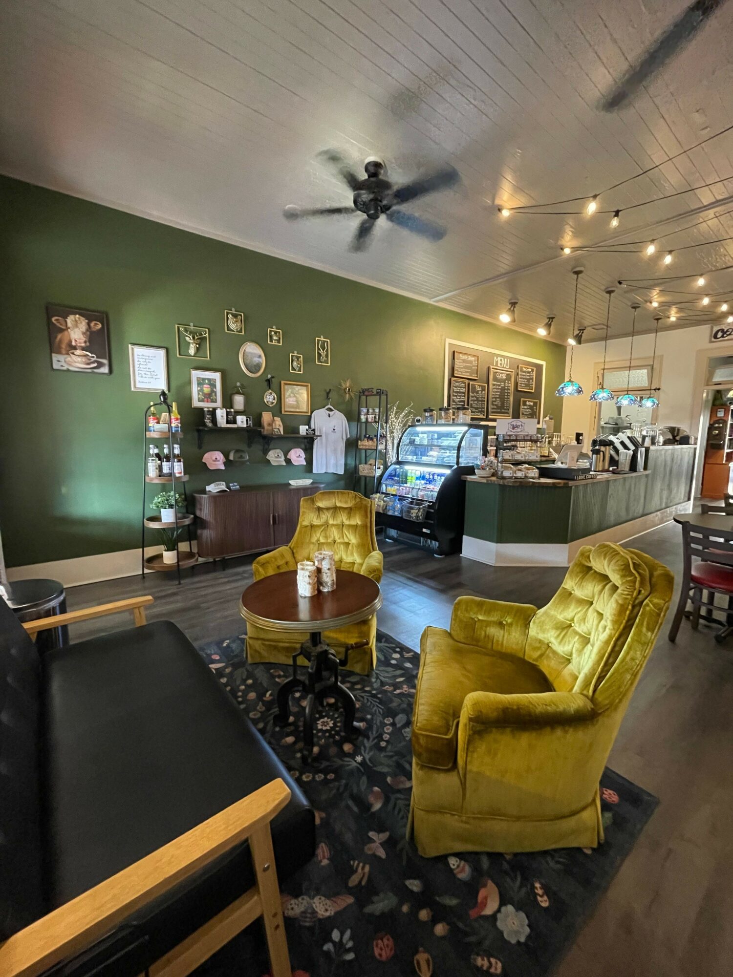 Living room with yellow armchair, green wall, and a bar area with bottles and glasses, decorated with string lights.