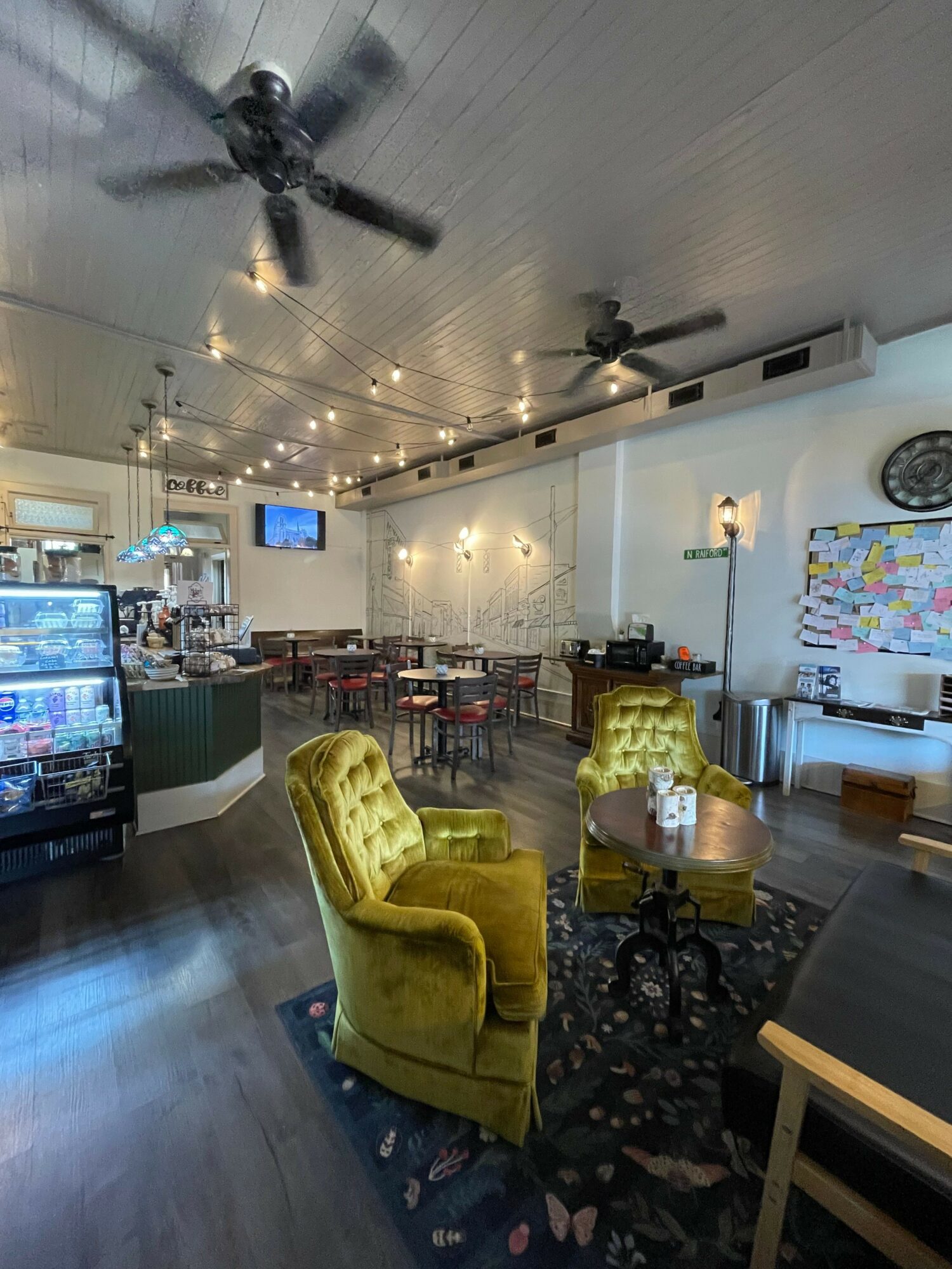 Cozy cafe interior with yellow armchair, bar counter, and hanging lights, viewed from a tilted angle.