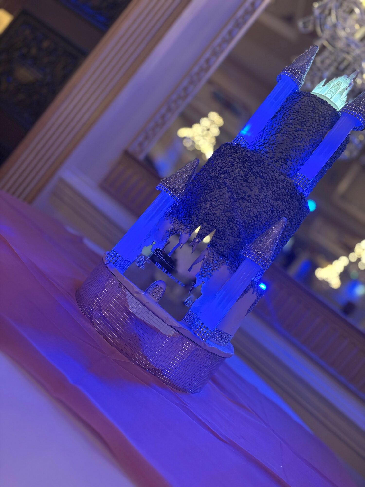 Decorative centerpiece with blue lighting, flowers, and candles on a table in an elegant room.