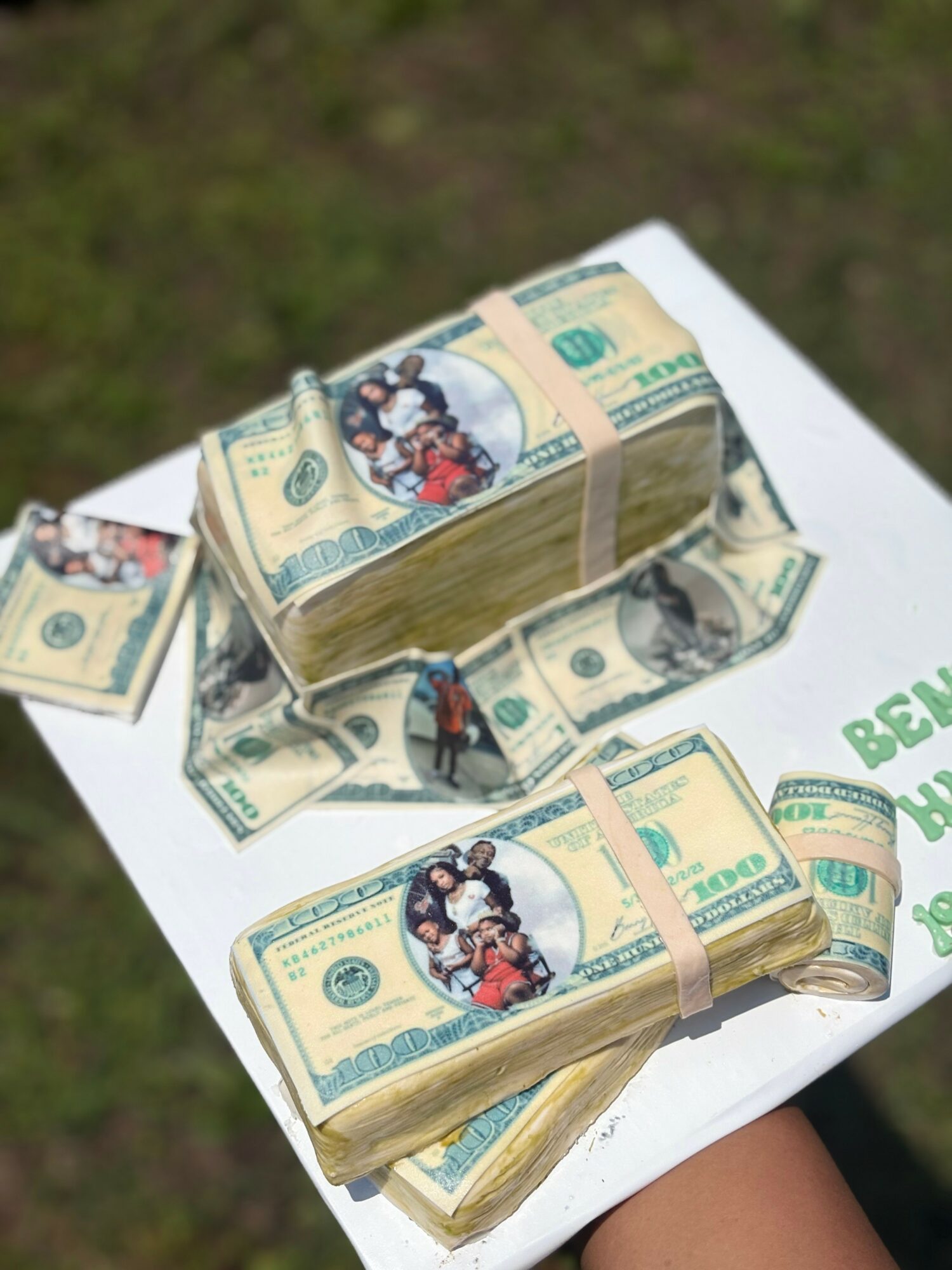 Stacks of US dollar bills with a cartoon image of people, placed on a white surface outdoors.
