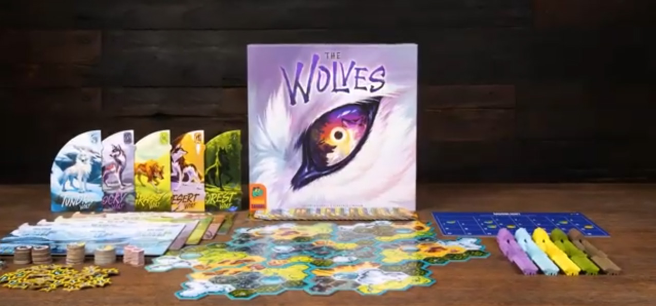 Board game components including cards, tokens, and game pieces arranged on a table, with a game box titled 'Wolves' in the background.