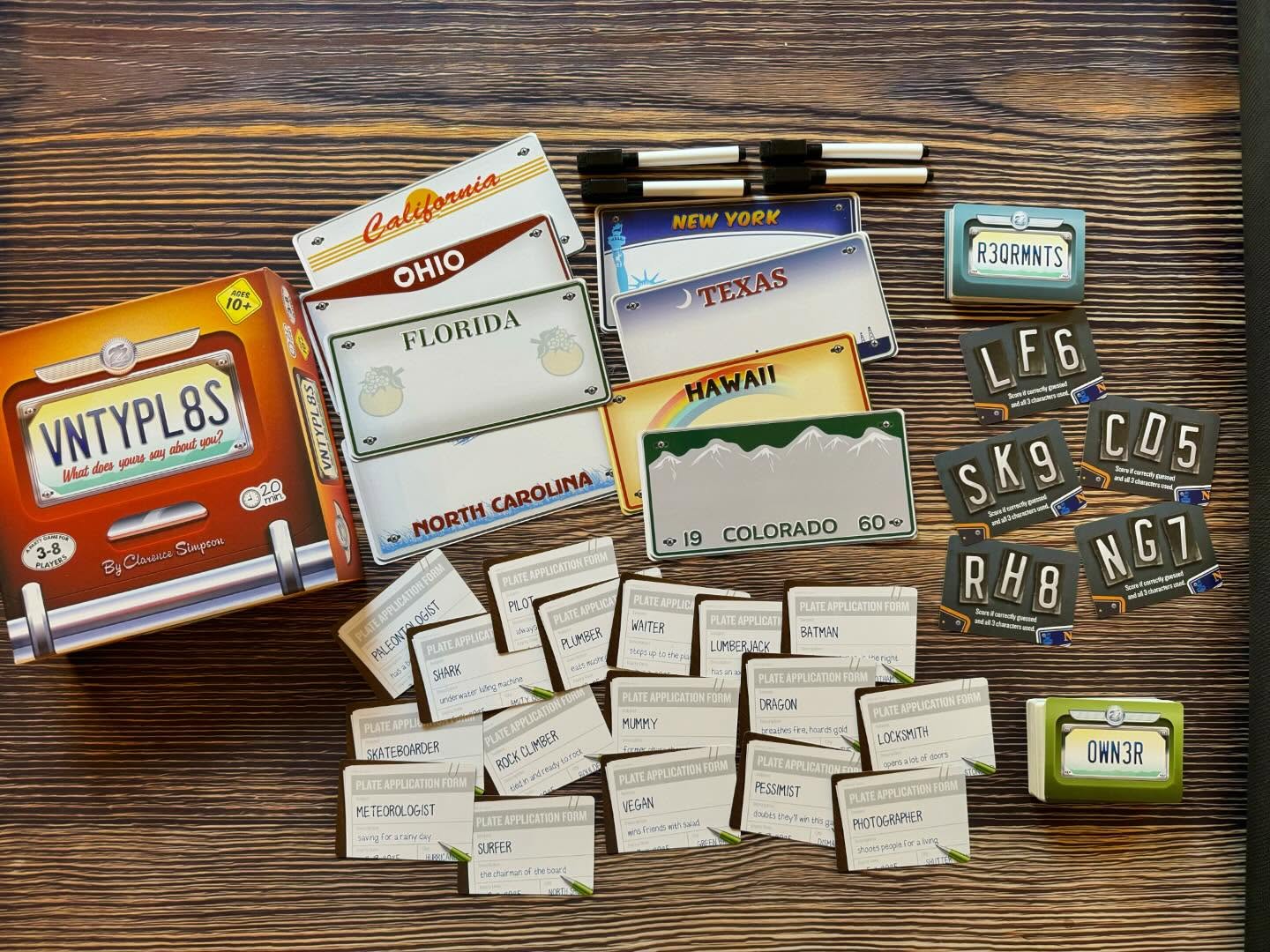 Collection of vintage license plates, tags, and pens on a wooden surface, with some plates from Ohio, Florida, Texas, Hawaii, and Colorado.