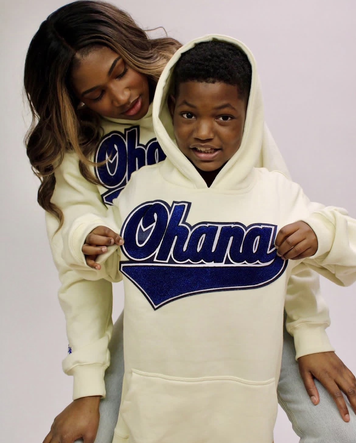 A woman and a boy wearing matching hoodies with the word 'Ohana' printed on them, posing together.