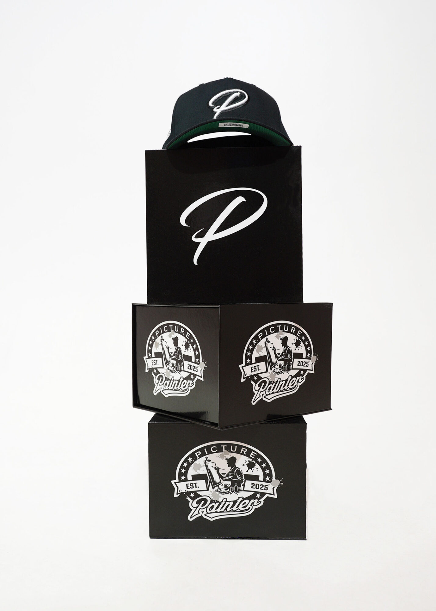 Black cap with white logo on top of black boxes with logos, against a white background.