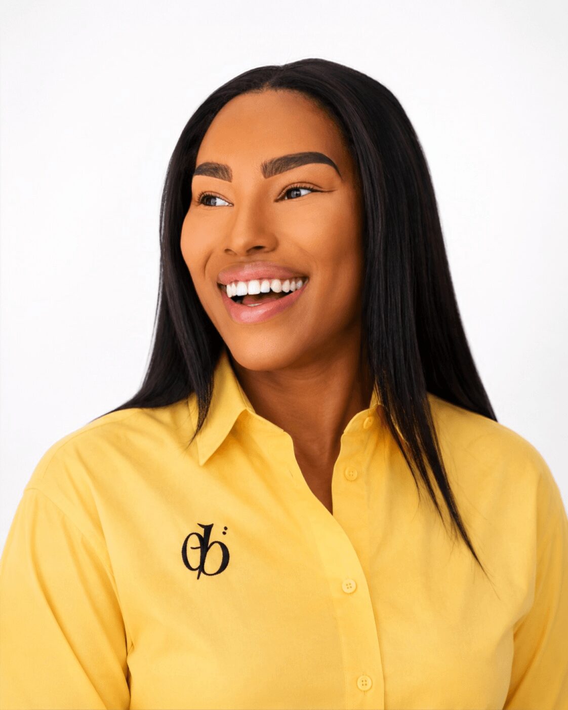 Smiling woman with long black hair wearing a yellow shirt against a white background.