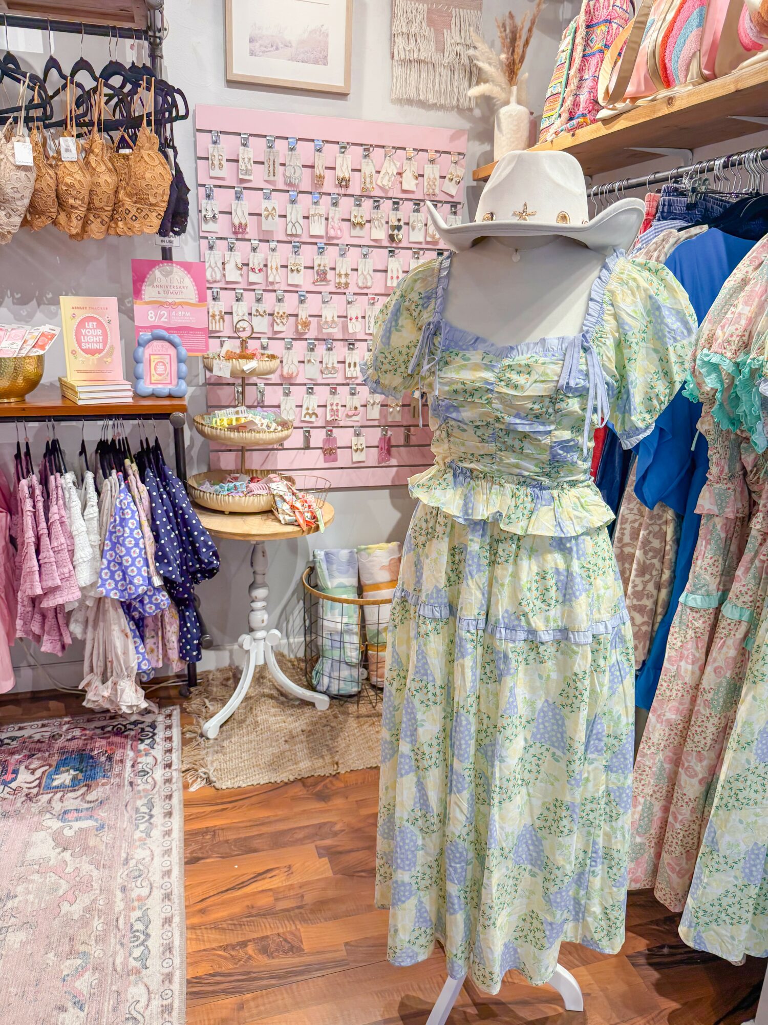 Mannequin dressed in a pastel-colored, patterned dress with puffed sleeves, in a boutique with clothing and accessories displayed.