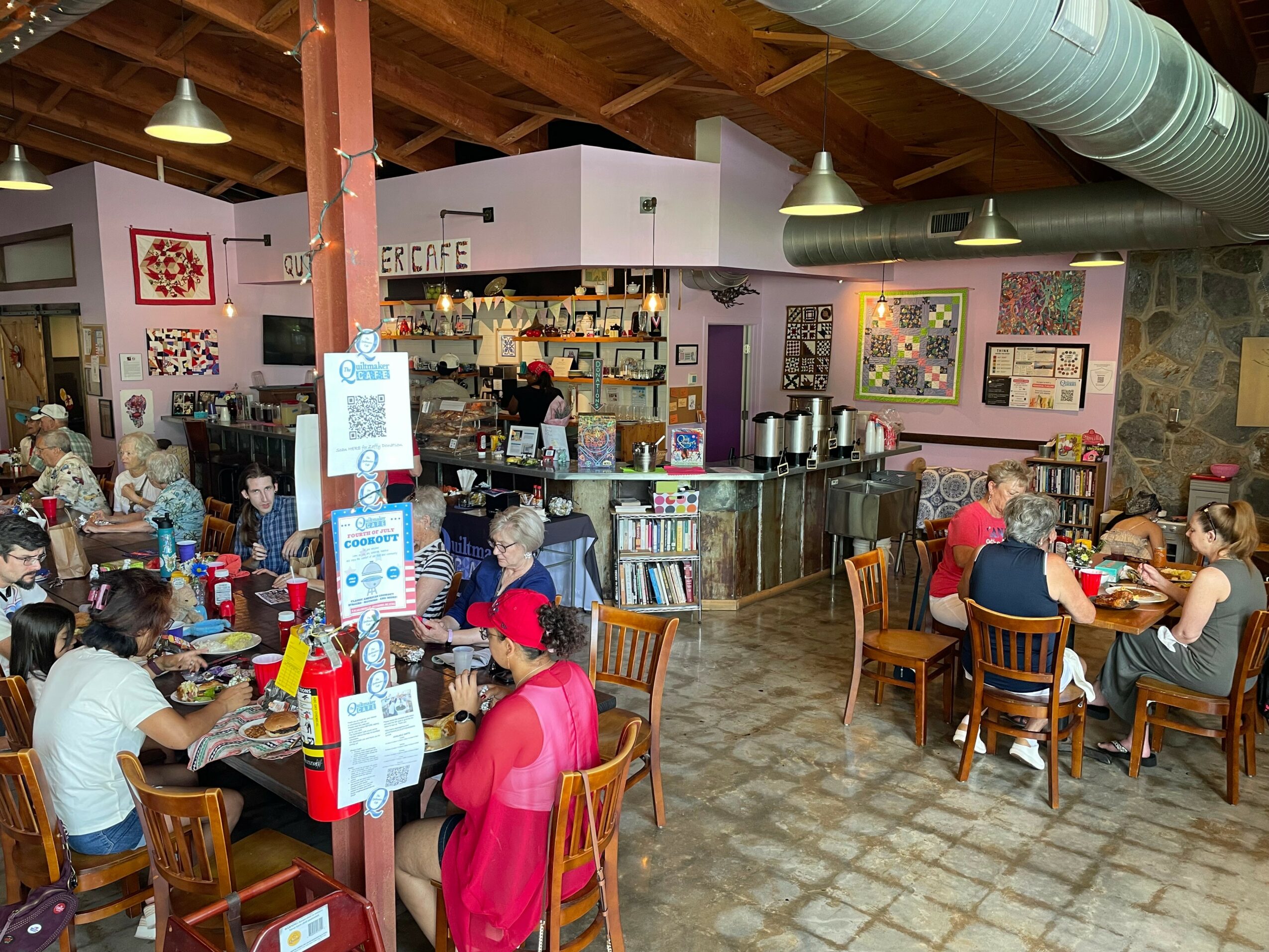 People sitting at tables in a cozy cafe with bookshelves and artwork on the walls.