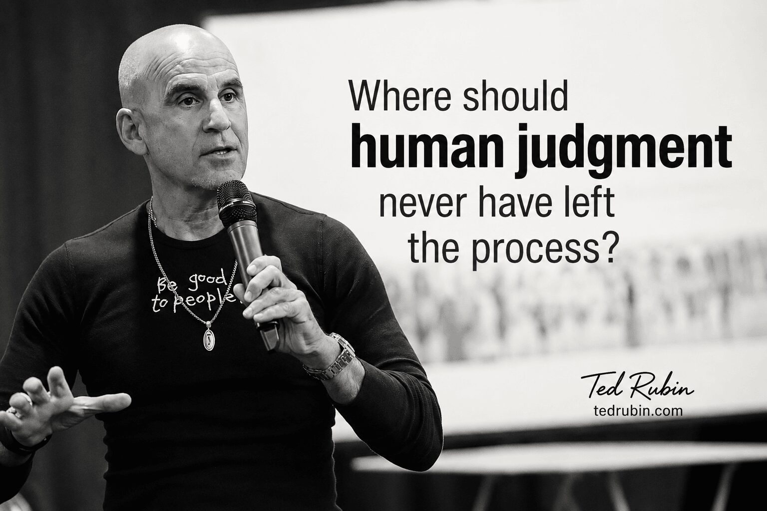 Bald man holding a microphone, wearing a black shirt with white text, speaking in front of a presentation slide about human judgment.
