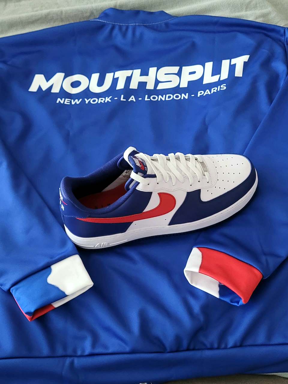 Blue sports jersey with white text, a white and red sneaker with navy blue accents, and red and white cuffs.